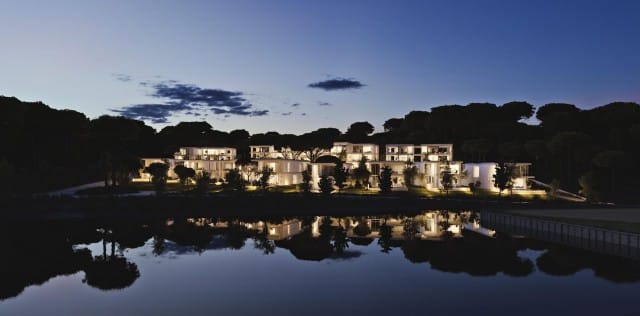 Vista exterior y nocturna de la promoción de apartamentos y casas en PGA Catalunya con ventanas minimalistas | Alumilux