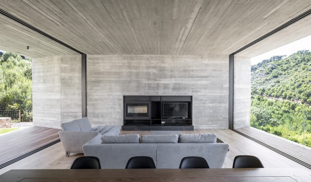 Casa 1510. Salón con amplios ventanales que incluye chimenea y espacio para el televisor . NordEst Arquitectura | Alumilux