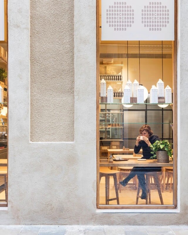 Hotel Casa Cacao | Clienta tomando un caco a la taza vista a través de una ventana Ottima | cAllís mArès arquitectes
