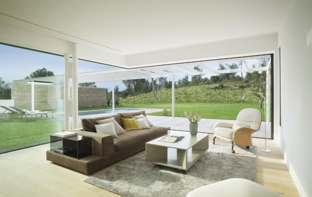 La Pineda | Salón con sofá y butaca con ventanal esquienro Ottima hacia el jardín | Jaime Prous Architects | Alumilux