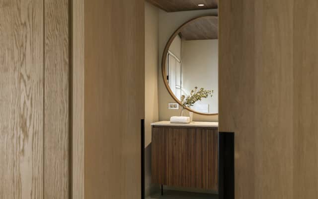Hotel Casa Cacao | Acceso al baño con espejo circular de una de las habitaciones | cAllís mArès arquitectes